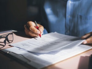 person prüft unterlagen mit einem stift