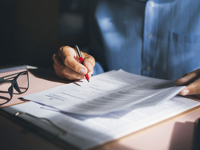 person prüft unterlagen mit einem stift