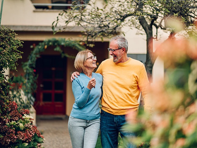 Älteres Paar mit Hausschlüssen in der Einfahrt des Hauses: Verkauf in der Zinswende