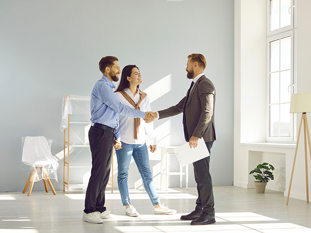 Junges Paar schüttelt die Hand des Maklers beim Immobilienkauf