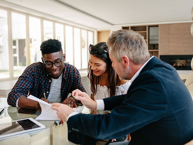 Junges Paar wird vom Makler zum Mietvertrag beraten